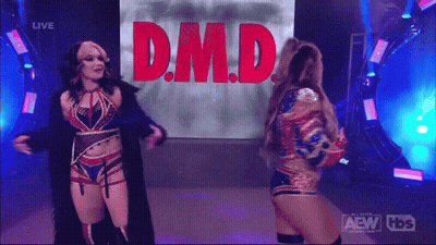 Two Female Wrestlers In Front Of Screen Saying D.M.D GIF