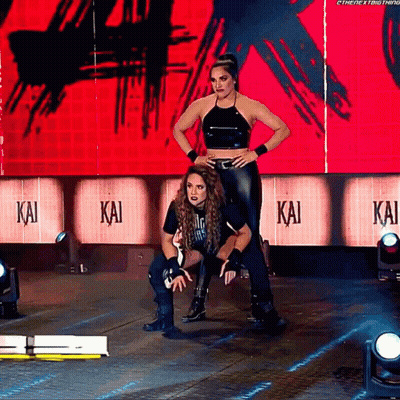 Two Female Wrestlers On Stage With Kai On Wall GIF