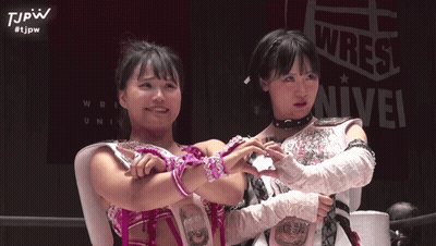 Two Female Wrestlers Posing In Front Of Wrest Sign GIF
