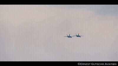 Two Fighter Jets Flying In A Cloudy Sky With Ernest Gutschik Aviation Written On The Bottom Right GIF