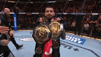 Two Fighters Holding Up Their Ufc Belts In Front Of A Bud Light Banner GIF