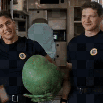 two firefighters are standing next to each other holding a large green object