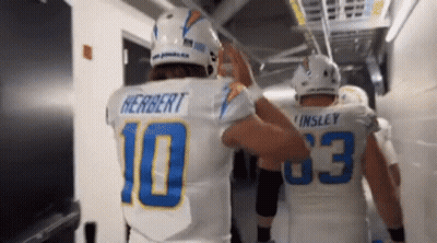 Two Football Players Are Giving Each Other A High Five In A Tunnel . GIF