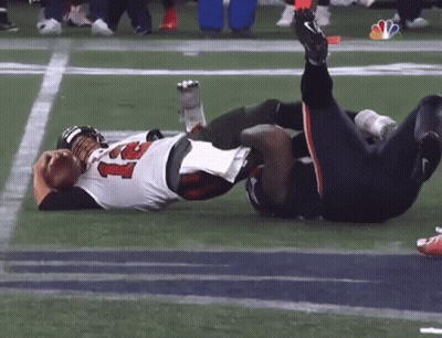 Two Football Players Are Laying On The Field With One Wearing A Jersey With The Number 22 On It GIF