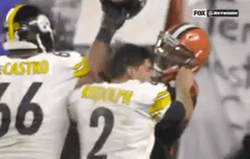 Two Football Players Are Standing Next To Each Other On A Field . GIF