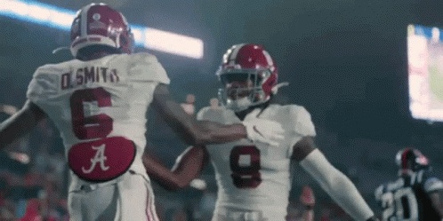 Two Football Players Are Standing Next To Each Other On A Field . GIF