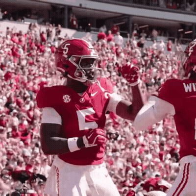 Two Football Players High Fiving In Front Of Crowd GIF