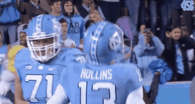 Two Football Players Hugging Each Other In Front Of A Crowd GIF