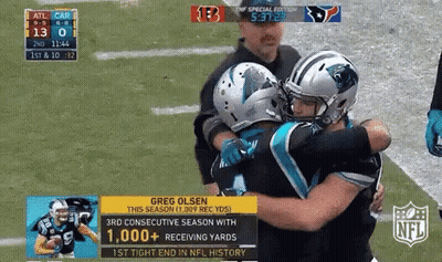 Two Football Players Hugging Each Other On The Field With The Nfl Logo In The Corner GIF