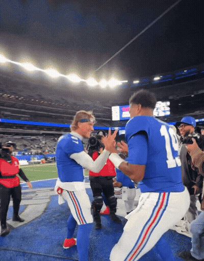 Two Football Players In Blue Uniforms With The Number 11 On The Back GIF