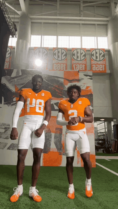 Two Football Players In Front Of Wall Banner Saying Taer GIF