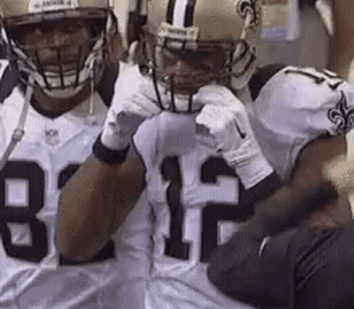Two Football Players In Helmets And Gloves Standing On Field GIF