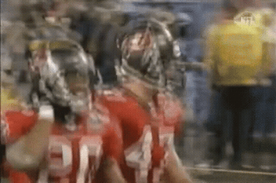 Two Football Players In Helmets Standing Side By Side GIF
