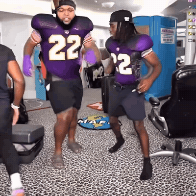 Two Football Players In Purple Uniforms With The Number 22 On Them GIF
