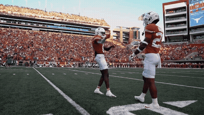 Two Football Players On A Field With A Scoreboard Behind Them That Says Texas Tech GIF