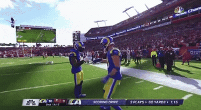 Two Football Players On A Field With A Scoreboard That Says Scoring Drive On It GIF