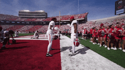 Two Football Players On Field With Cheerleaders GIF