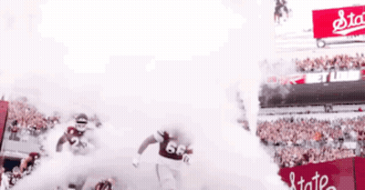 Two Football Players Running From Stadium Smoke GIF