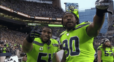 Two Football Players Wearing Green Jerseys With The Number 90 On Them GIF