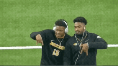Two Football Players Wearing Headphones Are Walking On The Field . GIF