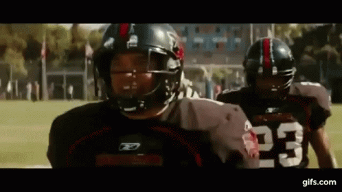 Two Football Players Wearing Helmets And Jerseys With The Number 23 On Them Are Walking On A Field . GIF