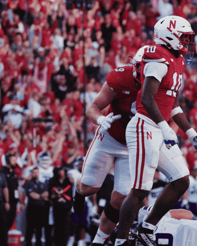 Two Football Players Wearing Red And White Uniforms With The Letter N On Their Helmets GIF