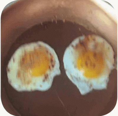Dos huevos fritos cocinándose en sartén con aceite GIF