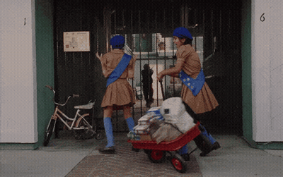 Two Girl Scouts Pushing Wheelbarrow Past Building Number 6 GIF