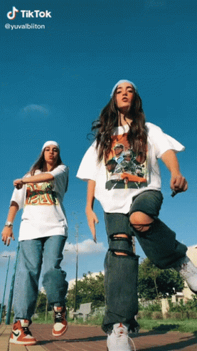 Two Girls Are Dancing In Front Of A Blue Sky With Tiktok Written At The Top GIF