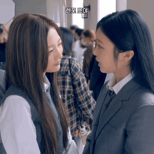 Two Girls Are Looking At Each Other In A Hallway With Korean Writing On The Bottom Right Corner GIF