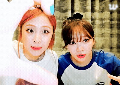 Two Girls Are Making A Heart Shape With Their Hands And One Of Them Is Wearing A Shirt That Says ' Rock ' GIF