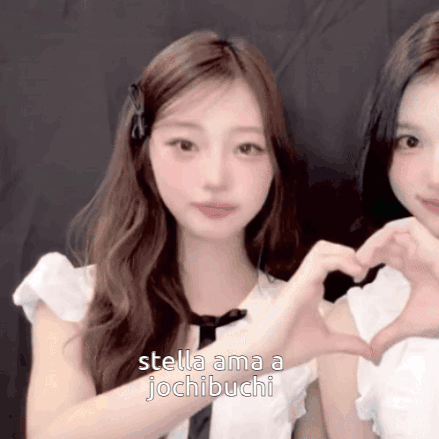 Two Girls Are Making A Heart Shape With Their Hands And The Words Stella Ama A Jochibuchi Are Visible GIF