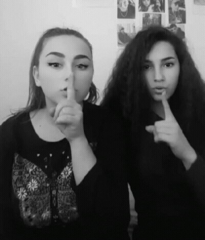 Two Girls Are Posing For A Picture And One Is Holding Her Finger To Her Lips GIF