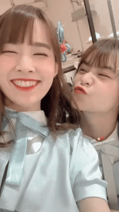 Two Girls Are Posing For A Picture And One Is Kissing The Other 'S Cheek GIF