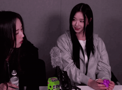 Two Girls Are Sitting At A Table With A Box Of Gummy Bears GIF