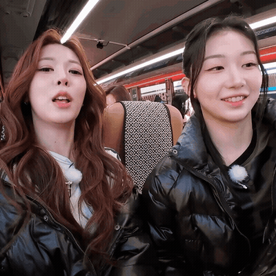 Two Girls Are Sitting Next To Each Other On A Bus And Smiling For The Camera GIF