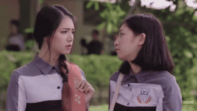 Two Girls Are Standing Next To Each Other And Talking To Each Other In A Park . GIF
