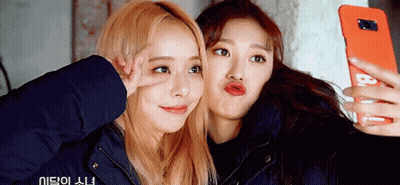 Two Girls Are Taking A Selfie With A Cell Phone That Says B On It GIF