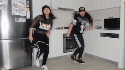 Two Girls Dancing In Kitchen Wearing Loud Shirts GIF