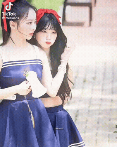 Two Girls In Blue Dresses Standing On Sidewalk GIF