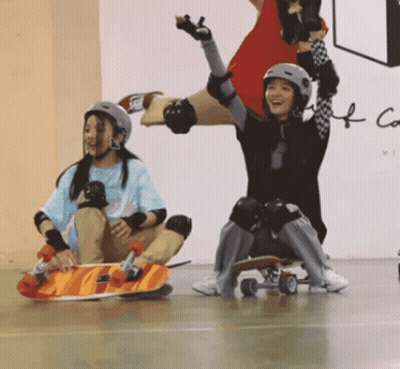 Two Girls In Helmets And Knee Pads On Skateboards GIF
