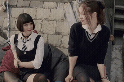 Two Girls In School Uniforms Sitting Next To Each Other GIF