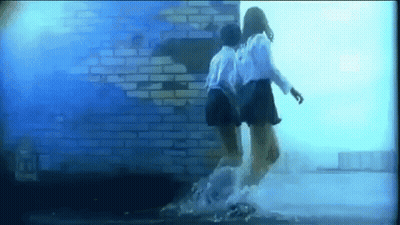 Two Girls Jumping In Water In Front Of Brick Wall GIF