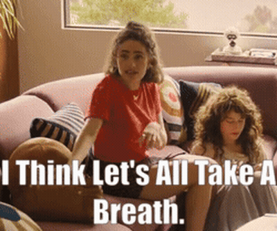Two Girls On Couch Saying I Think Let's All Take A Breath GIF
