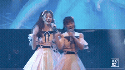 Two Girls On Stage Holding Microphones GIF
