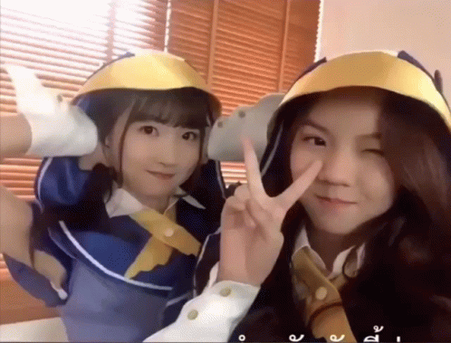 Two Girls Posing, One In Yellow Helmet GIF