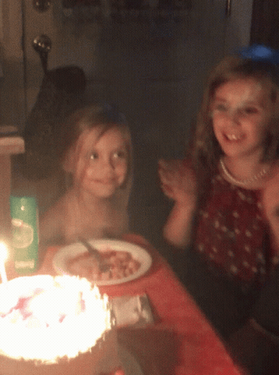 Two Girls Sitting at Table with Food and Living Box