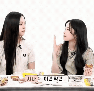Two Girls Sitting At Table With Sign Saying A GIF