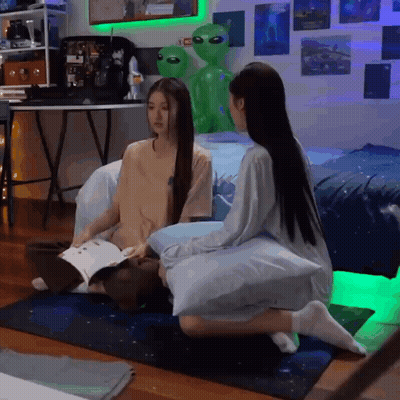 Two Girls Sitting On Floor With Green Alien Statue GIF
