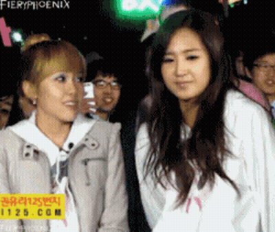 Two Girls Standing Beside Fieryphoenix Sign GIF